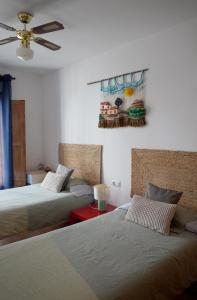 a bedroom with two beds and a painting on the wall at Casa Herminia in Frigiliana