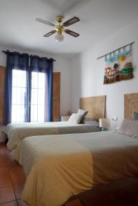 a bedroom with two beds and a ceiling fan at Casa Herminia in Frigiliana
