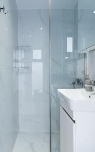 a white bathroom with a shower and a sink at Studio D1 in Kallithea Halkidikis