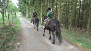 two people riding horses down a dirt road at B&B Les Paddocks in Vollore-Montagne
