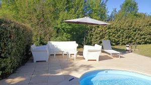 patio con sedie e ombrellone accanto alla piscina di Le Paradis de l'Ibie a Saint-Maurice-dʼIbie
