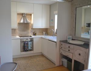 een keuken met witte kasten, een wastafel en een oven bij Marine Haven in Ballycastle