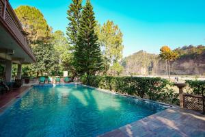 a swimming pool in a yard with trees at River Access Resorts by Bel-La Monde - "A Unit of Luxe Opera Hotels & Resorts", Dhikhuli Jim Corbett, Uttarakhand in Garjia