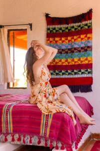 a woman in a dress sitting on a bed at Finca Luna Serena in San Miguel de Allende +10 photos