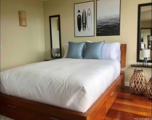 a bedroom with a large white bed with blue pillows at Makaha Valley Oasis 1-Bedroom apts in Waianae