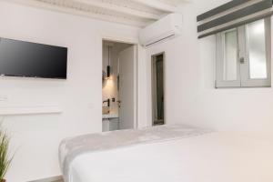 een witte kamer met een bed en een tv aan de muur bij August Mykonos in Mykonos-stad