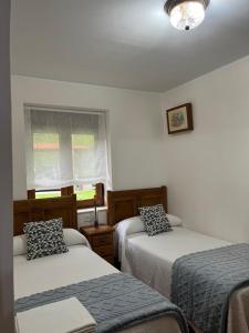 a bedroom with two beds and a window at Apartamentos Rurales Los Villares in Colunga