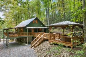 una cabaña verde en el bosque con cenador en Beside Still Water 1, en Cosby