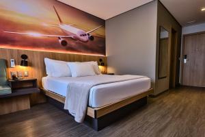a bedroom with a large bed with a painting of an airplane at Hotel Panamby Guarulhos in Guarulhos +24 photos
