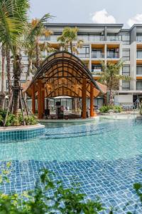 a swimming pool with a gazebo next to a building at Stylish Beachfront 2BR Flat in Nai Thon Beach