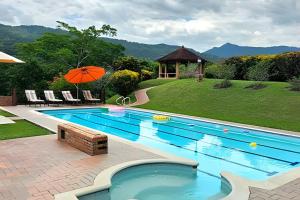 a swimming pool with a gazebo and an umbrella at Reserva tu casa rodeada de naturaleza en Villeta in Villeta