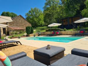 a swimming pool with chairs and umbrellas at Larroque Haute Gites in Cassagnes
