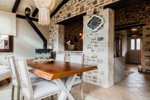 a dining room with a stone wall and a wooden table and chairs at Μάραθος in Kalavrita