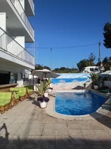 a swimming pool next to a building with an umbrella at Gasthaus Orsi in San Francesch