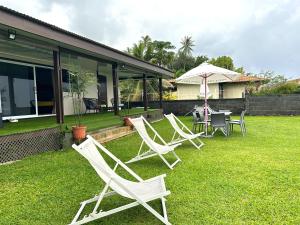 a group of lawn chairs and an umbrella on a yard at Hava'e Lodge TEAHUPOO in Teahupoo