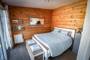 ein Schlafzimmer mit einem Bett in einem Zimmer mit Holzwänden in der Unterkunft Le Cottage de la Doucette in Paimpont
