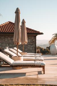 una fila de tumbonas con sombrillas en un patio en Rosal Country Village, en Ponte de Lima