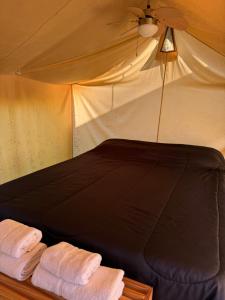 a bed in a tent with two towels at Glamping casa blanca in Campana