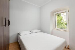 a white bedroom with a bed and a window at Branka R in Strp