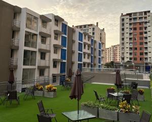 an apartment patio with tables and chairs and umbrellas at Apto con vista verde y aire acondicionado in Barranquilla