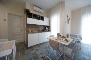 a kitchen with white cabinets and a table and chairs at Slow Chic Apartment Papardo in Messina