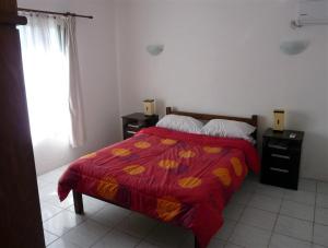 1 dormitorio con 1 cama con manta roja y ventana en Casa Diego y Claudia, en Colonia del Sacramento