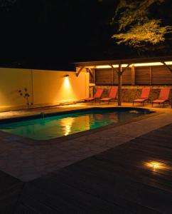 a swimming pool at night with chairs around it at Domaine Yacinthe in Le Robert