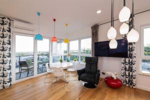 a dining room with a table and chairs and windows at Apartament River Tower in Bydgoszcz