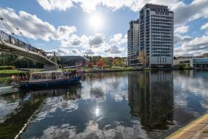 a boat on a river in front of a tall building at Apartament River Tower in Bydgoszcz