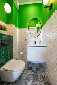 a bathroom with green walls and a toilet and a mirror at Apartament River Tower in Bydgoszcz