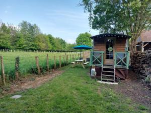 a small cabin with a picnic table and a blue umbrella at La 24h Roulotte in Parigné-lʼÉvêque +18 photos