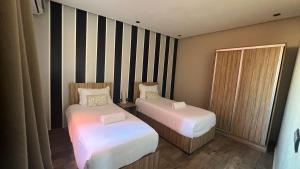Appartement 3 vue sur mer في تمراغت: سريرين في غرفة صغيرة بجدران مخططة
