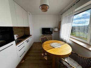 a small kitchen with a wooden table and a window at Apartament606 in Puszczykowo