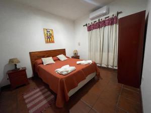 Departamento Cafayate في كفايات: غرفة نوم مع سرير وملاءات برتقالية ونافذة