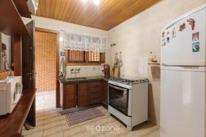 a kitchen with a stove and a refrigerator at Casa espaçosa c/lareira em Campos do Jordão RAS175 in Campos do Jordão