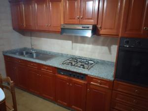 a kitchen with wooden cabinets and a stove and a sink at Road in Palas de Rei