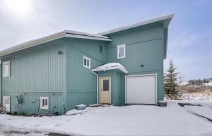 a green house with a garage in the snow at Scenic and Cozy Sweet Northern Comfort in Homer! in Homer