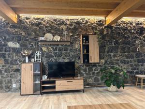 a living room with a tv and a stone wall at Casa Rural IRAMAR in Guardamino