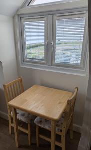 a wooden table and two chairs in a room with two windows at The Crow's Nest in Mundesley +5 photos