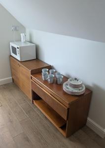 a table with cups and plates and a microwave at The Crow's Nest in Mundesley