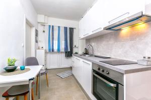 a kitchen with white cabinets and a table and a stove at Apartment New in Splitska +19 photos