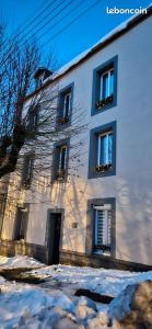 a white building with snow in front of it at La villa de l'Angle - Maison familiale de charme - jusqu'à 10 voyageurs in Le Mont-Dore