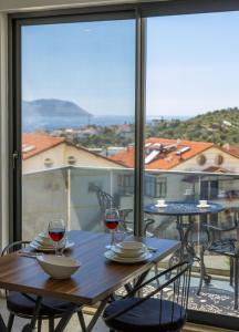 a wooden table with two glasses of wine on a balcony at Happy Kaş Apart in Kaş