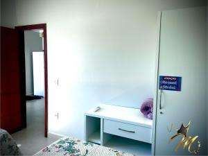 a room with a white desk and a refrigerator at Apt Completo e Confortável 300mt Praia de Croa Vermelha in Coroa Vermelha