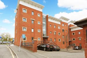 a red brick building with two cars parked in front of it at Albion Street Apartments in Wolverhampton
