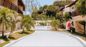 a walkway with palm trees next to a building at Flat Solar Água Bali by Qavi in Pipa