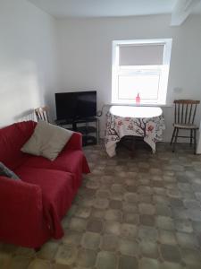 a living room with a red couch and a table at Village haven in Ballyroan