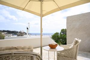 a patio with an umbrella and a table and chairs at Kanala Sea-Side Cycladic Cottage II in Kanala