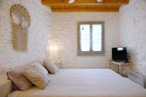 a bedroom with a large white bed with a television at Cycladic Cottage II in Kanala