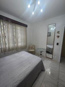 una camera da letto con un letto, un tavolo e uno specchio di Apartamento Aconchegante e Completo em Joinville - Aluguel por Dia a Joinville